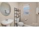 Well-lit half bathroom featuring modern fixtures, neutral walls, a round mirror, and a window at 3230 Richway Ct, Charlotte, NC 28216