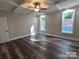 This primary bedroom boasts stylish tray ceilings with ceiling fan, hardwood flooring, and double windows at 404 Imperial Way, Albemarle, NC 28001
