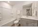 Bathroom features a shower-tub combo, white vanity with grey cabinets, and neutral decor at 4548 Millennium Ave, Charlotte, NC 28217