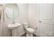 Cozy half bath features a pedestal sink, round mirror, and neutral finishes at 4548 Millennium Ave, Charlotte, NC 28217