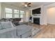 Cozy living room with a sectional sofa, fireplace, large windows, ceiling fan, and hardwood floors at 9432 Liberty Hill Dr, Mint Hill, NC 28227