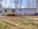Rear view of home with a small wooden deck, access door to the crawlspace, and gray vinyl siding at 1085 Cedar Hill Dr, Rockwell, NC 28138