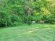 Well-manicured back yard featuring lush greenery, flowers, and trees at 202 Oakwood St, Stanfield, NC 28163