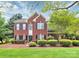 Charming two-story red brick home featuring a well-manicured lawn and established landscaping at 2217 Heath Lake Dr, Mint Hill, NC 28227