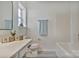 Clean white bathroom with a tub, toilet, and a vanity with a framed mirror and natural light at 3099 Windsor Trace Dr, Fort Mill, SC 29707