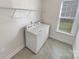 Functional laundry room with washer, dryer, wire shelving, and a window for natural light at 6234 Artigas Dr, Fort Mill, SC 29707
