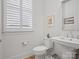Well-lit half bathroom with pedestal sink, stylish mirror, and shuttered window at 82116 Standing Oak Dr, Charlotte, NC 28278