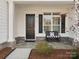 Inviting front porch with stone base, bench seating, and a stylish black front door at 82116 Standing Oak Dr, Charlotte, NC 28278