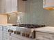 Close-up of a stainless steel gas range, custom cabinetry, and gray herringbone backsplash in a modern kitchen at 82116 Standing Oak Dr, Charlotte, NC 28278