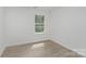 Bright bedroom featuring wood-look flooring, a window with natural light, and crisp white walls at 901 Cathey Rd, Charlotte, NC 28214
