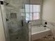 Bathroom featuring modern tiled walk-in shower, tub, and window at 1043 Boxelder Ln, Charlotte, NC 28262