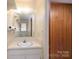 Bathroom with white single sink vanity and wood paneled door at 107 S Myrtle Ave, China Grove, NC 28023