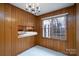 Wood paneled dining area features a chandelier, window, and opening to the kitchen with sink at 107 S Myrtle Ave, China Grove, NC 28023