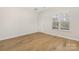 Bright living room features beautiful laminate floors, a large window, and neutral walls creating an open space at 11029 Ardglass Ct, Charlotte, NC 28213