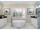 Bright bathroom featuring a soaking tub with window shutters and double vanity with black countertops at 20105 Chapel Point Ln, Cornelius, NC 28031