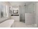 Modern bathroom featuring a sleek glass shower, double vanity, soaking tub and white marble tiling at 20105 Chapel Point Ln, Cornelius, NC 28031