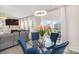 Open-concept dining area features a modern chandelier, glass table, and blue chairs with backyard views at 205 Falls Cove Dr, Troutman, NC 28166