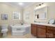 Bathroom featuring a corner soaking tub, white tile surround, and a vanity with sink at 468 White Oak Branch Rd, Statesville, NC 28625