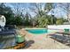 A backyard pool surrounded by mature trees with a deck and stone patio at 5908 Brookhaven Rd, Charlotte, NC 28210