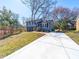 Two-story home with blue door, lush yard, long driveway, painted brick, and professional landscaping at 8208 Doverdale Ln, Charlotte, NC 28217