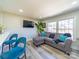 Open-concept living room with laminate flooring, a plush grey sofa, and large windows offering ample natural light at 8208 Doverdale Ln, Charlotte, NC 28217