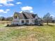 Back view of two-story home with a screened porch and attached garage, set on a large lot with mature trees and pond access at 107 Sunderland Dr, Shelby, NC 28150