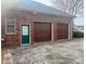 Attached two-car garage with wooden doors and brick exterior with stained door at 1217 12Th Fairway Nw Dr, Concord, NC 28027