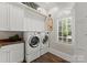 Convenient laundry room equipped with modern washer and dryer, storage cabinets, and a window at 131 The Point Dr, Mooresville, NC 28117