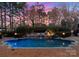 Sparkling pool with a waterfall feature, surrounded by lush greenery and a brick patio, creating a tranquil backyard oasis at 131 The Point Dr, Mooresville, NC 28117
