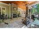 Inviting covered patio featuring a stone fireplace, ceiling fan, and comfortable seating area overlooking the backyard at 13215 Claysparrow Rd, Charlotte, NC 28278