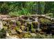 Backyard waterfall surrounded by lush greenery, moss-covered rocks, and mature trees create a peaceful and scenic view at 13215 Claysparrow Rd, Charlotte, NC 28278