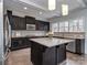 Modern kitchen featuring dark cabinetry, stainless steel appliances, a granite island, and ample natural light at 1400 Huntcliff Dr, Waxhaw, NC 28173