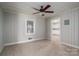Neutral living room with wood paneled walls, a ceiling fan, carpet flooring, and an open door frame at 1547 Kings Rd, Shelby, NC 28150