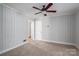 Neutral living room with wood paneled walls, a ceiling fan, carpet flooring, and a white door at 1547 Kings Rd, Shelby, NC 28150