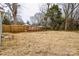 Large unfenced backyard with grass, mature trees, privacy fence, and residential neighborhood in distance at 343 Bell St, Mooresville, NC 28115