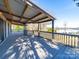 View of a spacious covered deck with wooden railings overlooking a serene lake on a sunny day at 4080 Elks Park Rd, Rock Hill, SC 29732