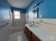 Bright bathroom with a full tub, white tile, and a classic vanity, offering a clean space for relaxation and grooming at 7201 Gilead Rd, Huntersville, NC 28078