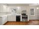 Well-lit kitchen features white cabinets, stainless steel appliances, and wood floors at 8730 Rittenhouse Cir, Charlotte, NC 28270