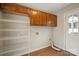 Laundry room with overhead cabinets, shelving, and white door to the exterior at 8730 Rittenhouse Cir, Charlotte, NC 28270