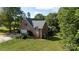 Aerial view of a well-kept brick home with a spacious yard, mature trees, and a detached garage at 912 Silver Charm Ln, York, SC 29745