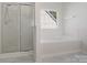 Bright bathroom features a glass shower and a soaking tub underneath a window at 10032 Montrose Nw Dr, Charlotte, NC 28269