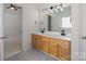Bright bathroom with dual sinks, wooden cabinets, and a large mirror at 10032 Montrose Nw Dr, Charlotte, NC 28269