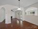 Open-concept living room with hardwood floors, arched doorways, and abundant natural light at 10032 Montrose Nw Dr, Charlotte, NC 28269