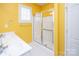 Bright yellow bathroom with a double vanity and glass-enclosed shower at 10034 Bishops Gate Blvd, Pineville, NC 28134