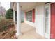 Spacious covered front porch featuring classic columns, red shutters and an inviting entryway at 10034 Bishops Gate Blvd, Pineville, NC 28134