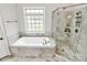 Bright bathroom with tub, tiled shower, and large window at 1011 Duntov Dr, Monroe, NC 28110