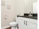 A half-bathroom features a white toilet, vanity with dark countertop, and framed artwork at 1011 Duntov Dr, Monroe, NC 28110