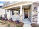 Inviting front porch with stone-accented columns leading to a modern black front door at 146 Prestwick Way # 20, Mooresville, NC 28115