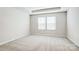 Light-filled bedroom featuring a tray ceiling, neutral carpet, and a large window at 2350 Hedgecliff Rd, Kannapolis, NC 28025