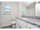 A bathroom has granite countertop, white cabinets, mirror, and a window bringing in natural light at 265 Duke Dr, Salisbury, NC 28146